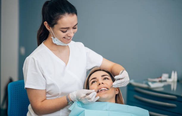 friendly dentist woman treating beautiful patient in dental office, doctor in white uniform, professional orthodontist